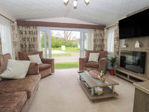 A living room with two sofas, a coffee table, a flat-screen TV, and a large window with curtains. - The Norfolk Nook 18 Castle Walk (Great Yarmouth)