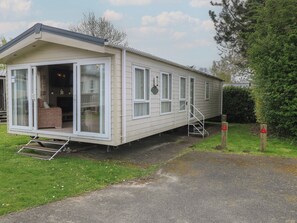 A mobile home with a front porch, a sliding door, and a small set of stairs leading to the entrance. - The Norfolk Nook 18 Castle Walk (Great Yarmouth)