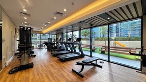 A gym with treadmills, a bench press, and a squat rack. - Skyline View High-Floor Apartment mit Pool (Dubai)