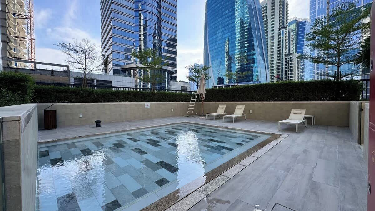 Una piscina sul tetto con lettini, circondata da edifici alti.