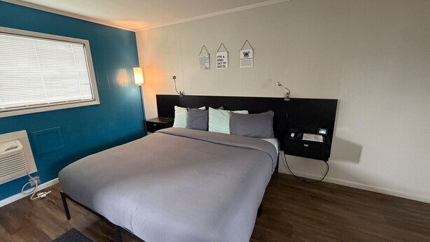 Een slaapkamer met een bed, nachtkastje, lamp en een tv aan de muur.