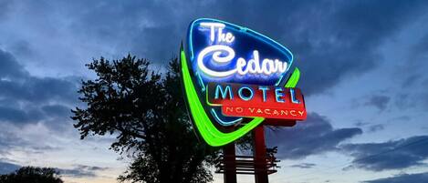 Ein Neon-Schild für das 'The Cedars Motel' mit einem 'Nicht verfügbar'-Schild darunter.