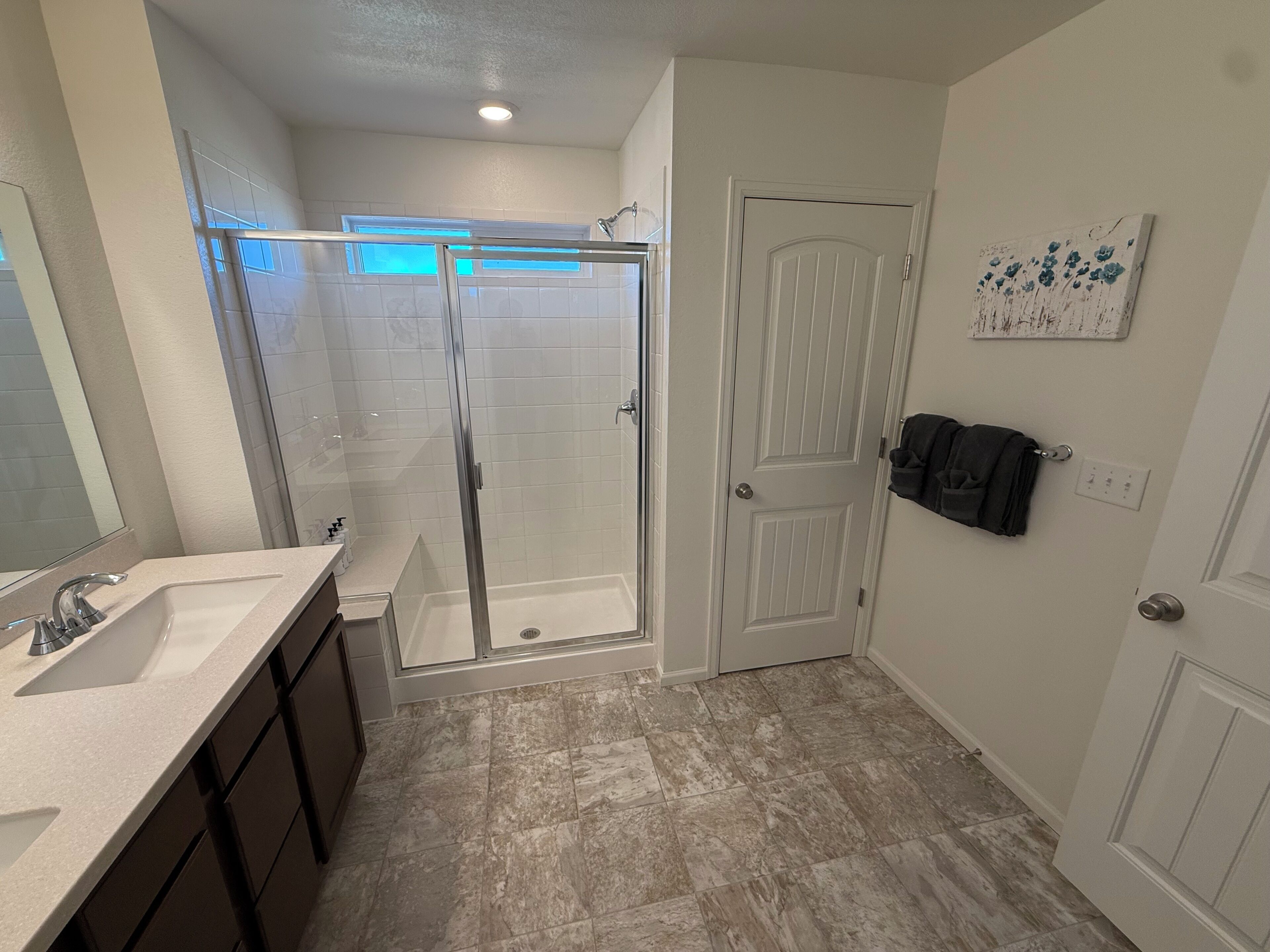 Une salle de bain avec une douche, un lavabo et des placards.