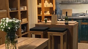 Una mesa de madera con bancos, un florero y un aparador con vajilla.