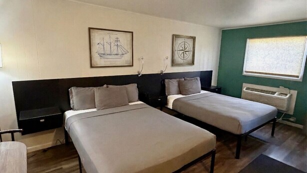 A room with two beds, a desk, and a window with blinds. - The Captain`s Room at The Cedar (Sandusky)