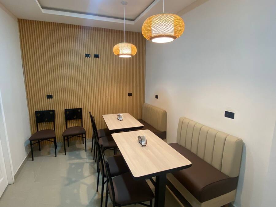 Un comedor moderno con una pared de acento de madera, una mesa larga con sillas y dos lámparas colgantes.