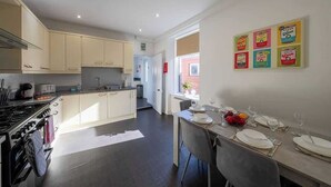A modern kitchen with a dining area, a stove, and a table set for four. - Balmoor House - 4 Beds in Peterhead near the coast (Aberdeenshire)