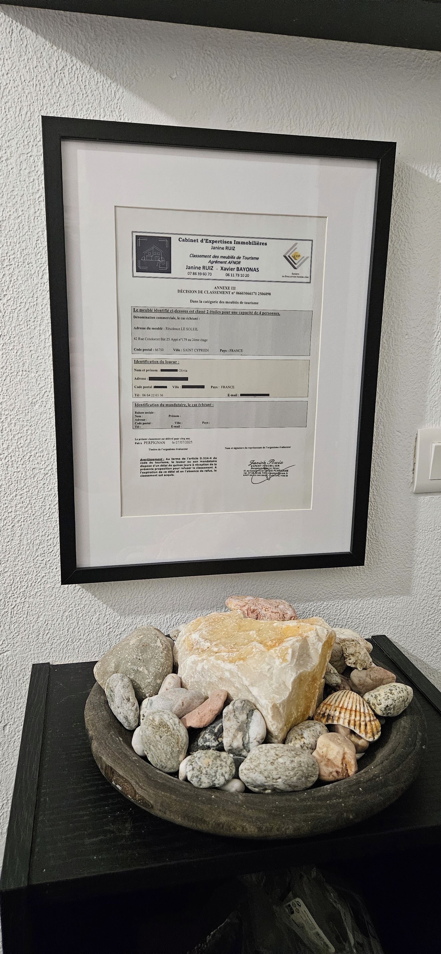 Un document encadré est accroché au mur, et un bassin en pierre se trouve en dessous.