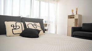Ett hotellrum med en säng, en soffa, ett nattduksbord och ett fönster med gardiner.