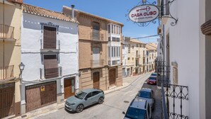 A street view with buildings, a parked car, and a sign for 'CASA CUBO VIVIENDA RURAL'.