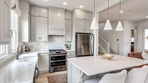 A modern kitchen with white cabinetry, stainless steel appliances, and pendant lighting. - Private Pickleball Resort | Waterfront | Golf Cart (Carlton Landing)