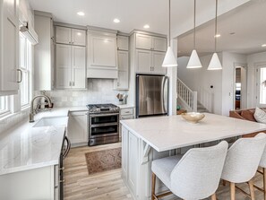 A modern kitchen with white cabinetry, stainless steel appliances, and pendant lighting. - Private Pickleball Resort | Waterfront | Golf Cart (Carlton Landing)