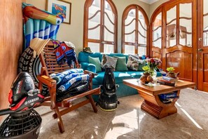 Ein Zimmer mit einem blauen Sofa, Holzmöbeln, einem Yamaha Staubsauger und einer Holztür mit Rundbogenfenstern.