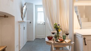 Et spiseområde med et bord dækket til to personer, et spejl på væggen og en trappe til højre.