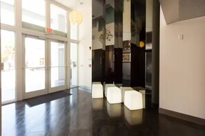 Eine moderne Lobby mit Glastüren, einem polierten Boden und einer Sitzecke mit weißen Stühlen.