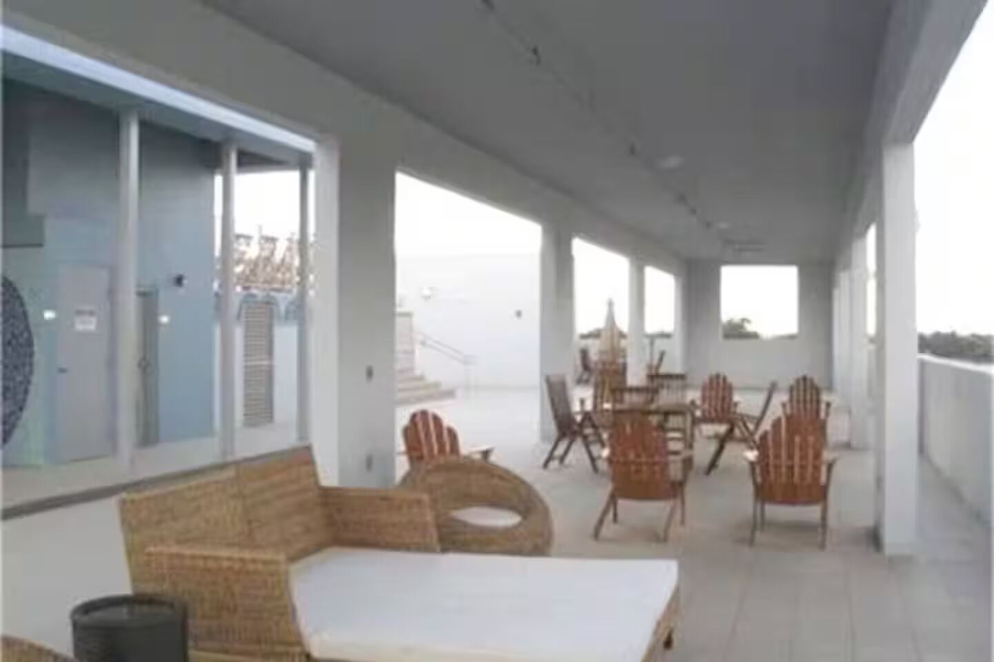 A covered outdoor area with a sofa, chairs, and a table.