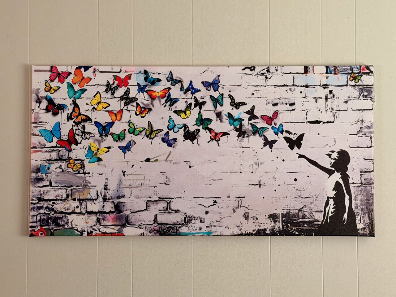 A wall with a graffiti-style painting of a person reaching out to butterflies.