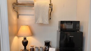 Une petite cuisine équipée d’un four à micro-ondes, d’une machine à café et d’une lampe, le tout posé sur un meuble en bois.