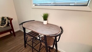Une table à manger avec des chaises, une plante en pot et une fenêtre avec des stores.