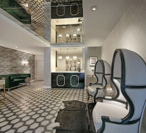 Eine geräumige Lobby mit einem geometrisch gemusterten Boden, einem grünen Sofa, einem Empfangsschalter und einer hohen Decke mit sechseckigem Design.