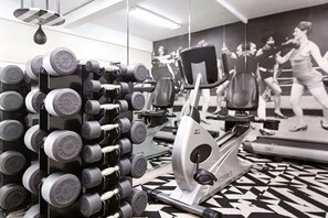 Ein Fitnessraum mit Wandstauraum für Hanteln, Cardiogeräten und einem gemusterten Boden.