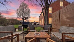 Eine Terrasse mit Gartenmöbeln, einem Tisch mit Gläsern und einem Grill.