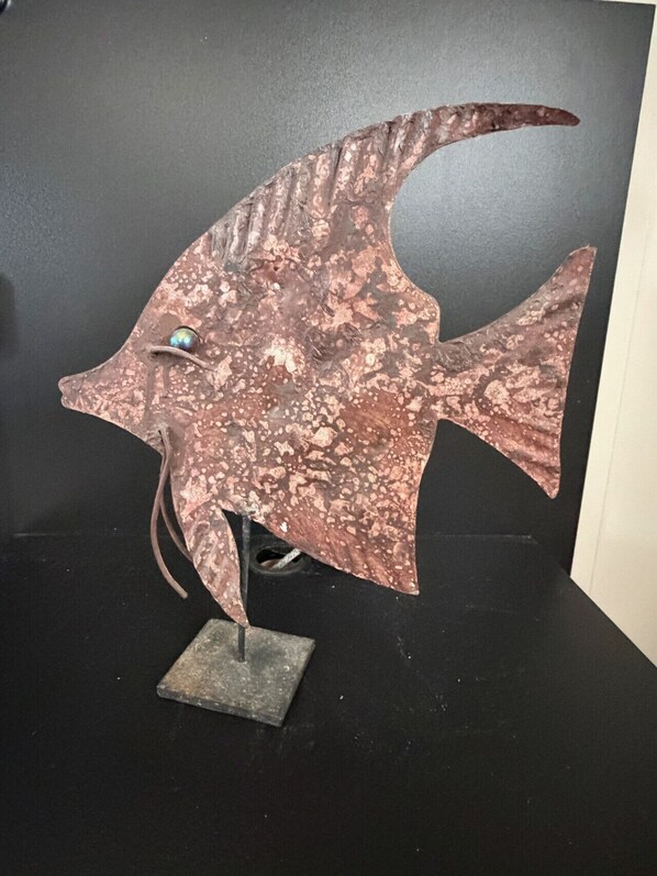 A metal sculpture of a fish on a black surface.