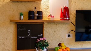Eine Küche mit einer Kreidetafel, einem roten Wasserkocher und einem Fernseher.