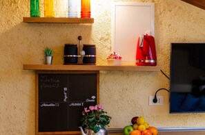 Eine Küche mit einer Kreidetafel, einem roten Wasserkocher und einem Fernseher.