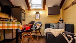Ein gemütliches Zimmer mit Esstisch, zwei Stühlen, einer Couch und einem Fernseher.