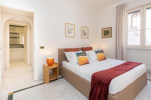 A bedroom with a large bed, a nightstand, a mirror, and a window with curtains. - San Trifone RiR Collection (Rome)