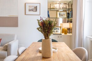 A wooden table with a vase of dried flowers, a framed picture on the wall, and a bookshelf in the background. - San Trifone RiR Collection (Rome)