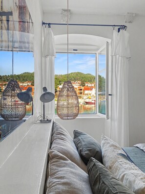 A room with a bed, hanging chairs, and a view of buildings and water. - Seafront — A Place Like No Other (Stari Grad)