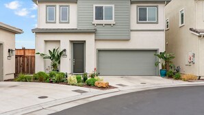 Un edificio residenziale a due piani con garage, un'entrata principale e un vialetto.