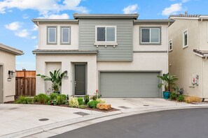 A two-story residential building with a garage, a front door, and a driveway. - Welcome  - Modern, North Sacramento Tropical Home (Sacramento)