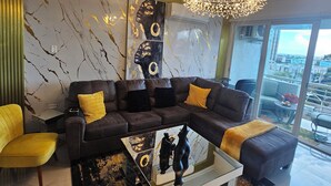 Ein modernes Wohnzimmer mit einer Eckcouch, einem Glastisch und einem Kronleuchter.