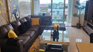 Ein modernes Wohnzimmer mit einer Ledersofa, einem Glastisch und einem großen Fenster mit Blick auf die Stadt.