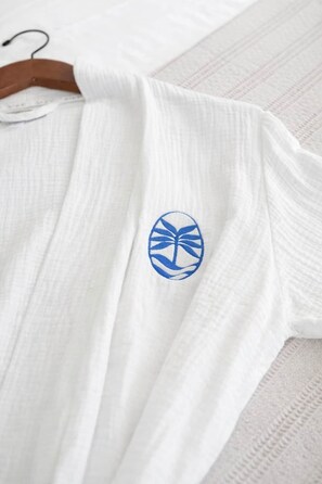 Ein weißes Kleidungsstück mit einem blauen Emblem auf der Brust.
