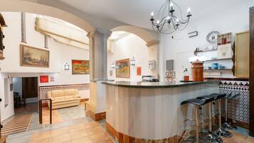 A bar area with a curved counter, bar stools, and a chandelier.