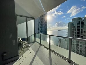 A balcony with a glass railing overlooking a cityscape and a body of water. - Amazing VIEW, Cornet unit Brickell 2 bed / 2 bath (Miami)