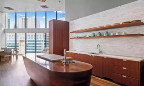 A modern kitchen with a central island, wooden cabinets, a white backsplash, and a view of buildings through large windows. - Amazing VIEW, Cornet unit Brickell 2 bed / 2 bath (Miami)
