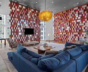 A modern living room with a blue sofa, a coffee table, and a TV. The walls are decorated with colorful geometric patterns. - Amazing VIEW, Cornet unit Brickell 2 bed / 2 bath (Miami)