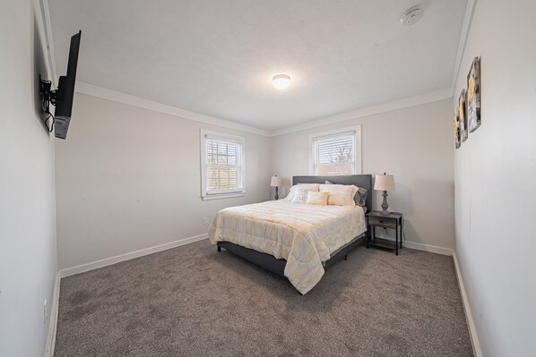 A bedroom with a bed, nightstands, a lamp, and a ceiling light.