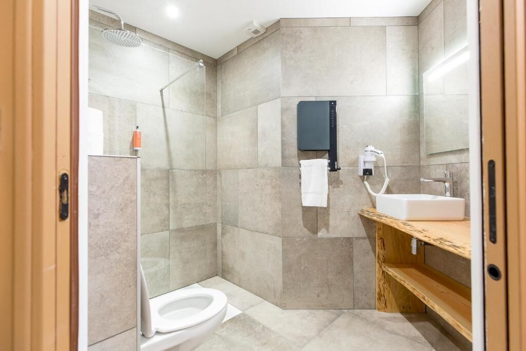 A modern bathroom with a glass shower enclosure, a toilet, a sink with a mirror, and a towel rack.