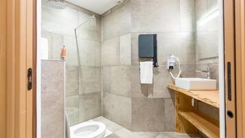A modern bathroom with a glass shower enclosure, a toilet, a sink with a mirror, and a towel rack.