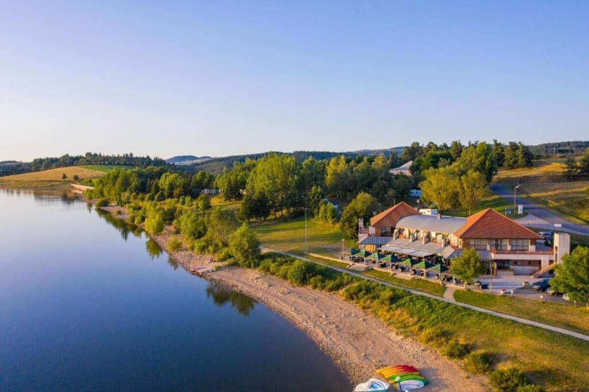 A lakeside hotel with a large building, a dock, and a boat.