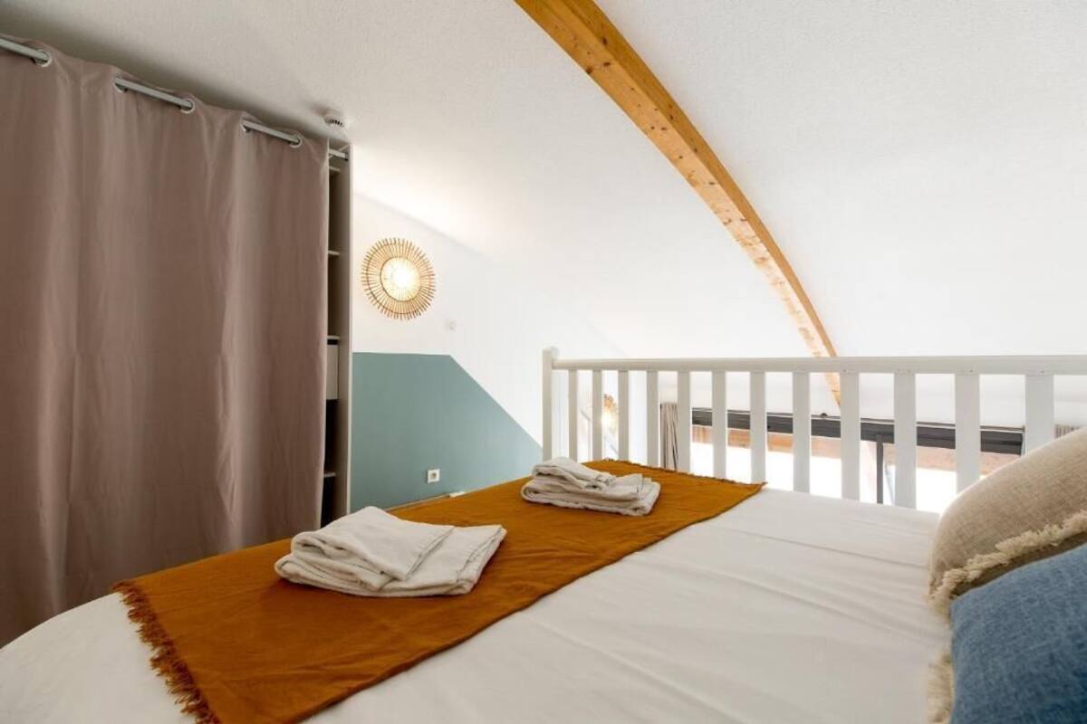 A bedroom with a bed, a brown throw blanket, and a white towel.