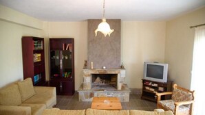Ein Wohnzimmer mit Kamin, Fernseher, Sofa und Bücherregal.