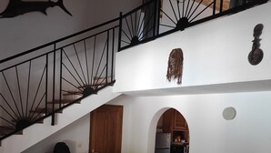 A dining area with a round table, chairs, a kitchen in the background, and a staircase with a railing. - Superb villa with private pool & wooded garden 500m from the beach in Nianing  (Nianing)