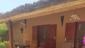A covered outdoor seating area with a table and chairs, a large planter, and a door with a glass panel. - Superb villa with private pool & wooded garden 500m from the beach in Nianing  (Nianing)